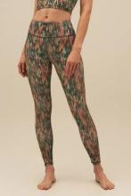 women wearing leggings which has greens, oranges, yellows and brown mixed together in an abstract rain-spired pattern on them all on a pale pink background 