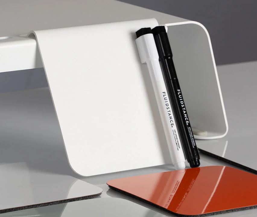 white angled panel against desks top riser with pens on it