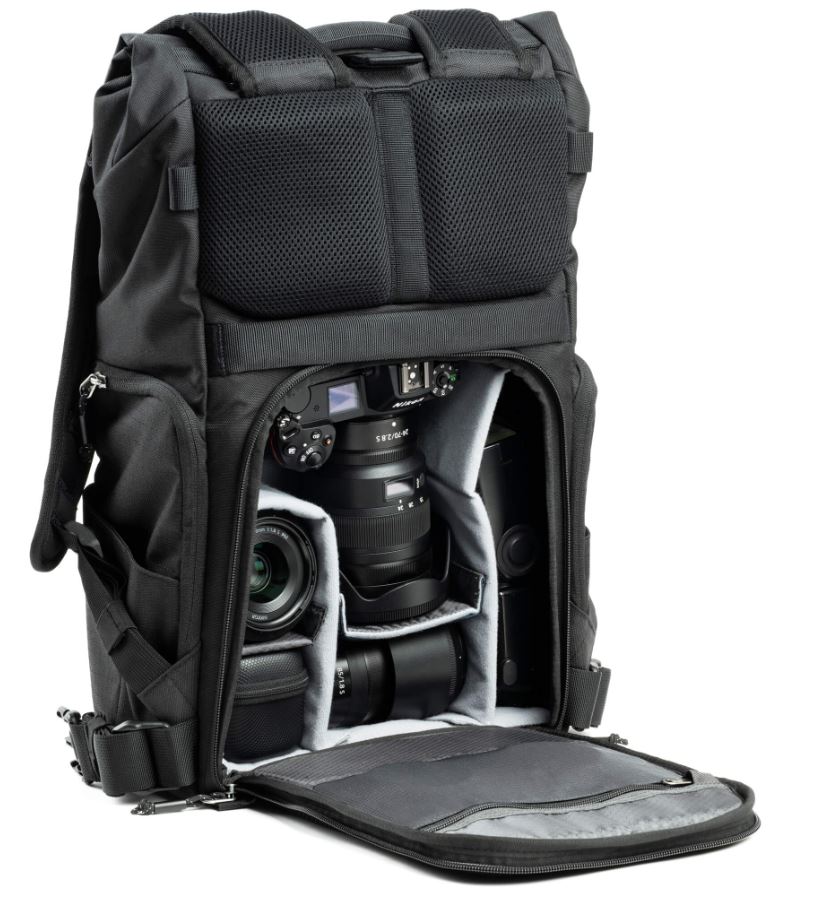 A black camera backpack with rear compartment open, revealing organized padded sections holding a DSLR camera and multiple lenses. 