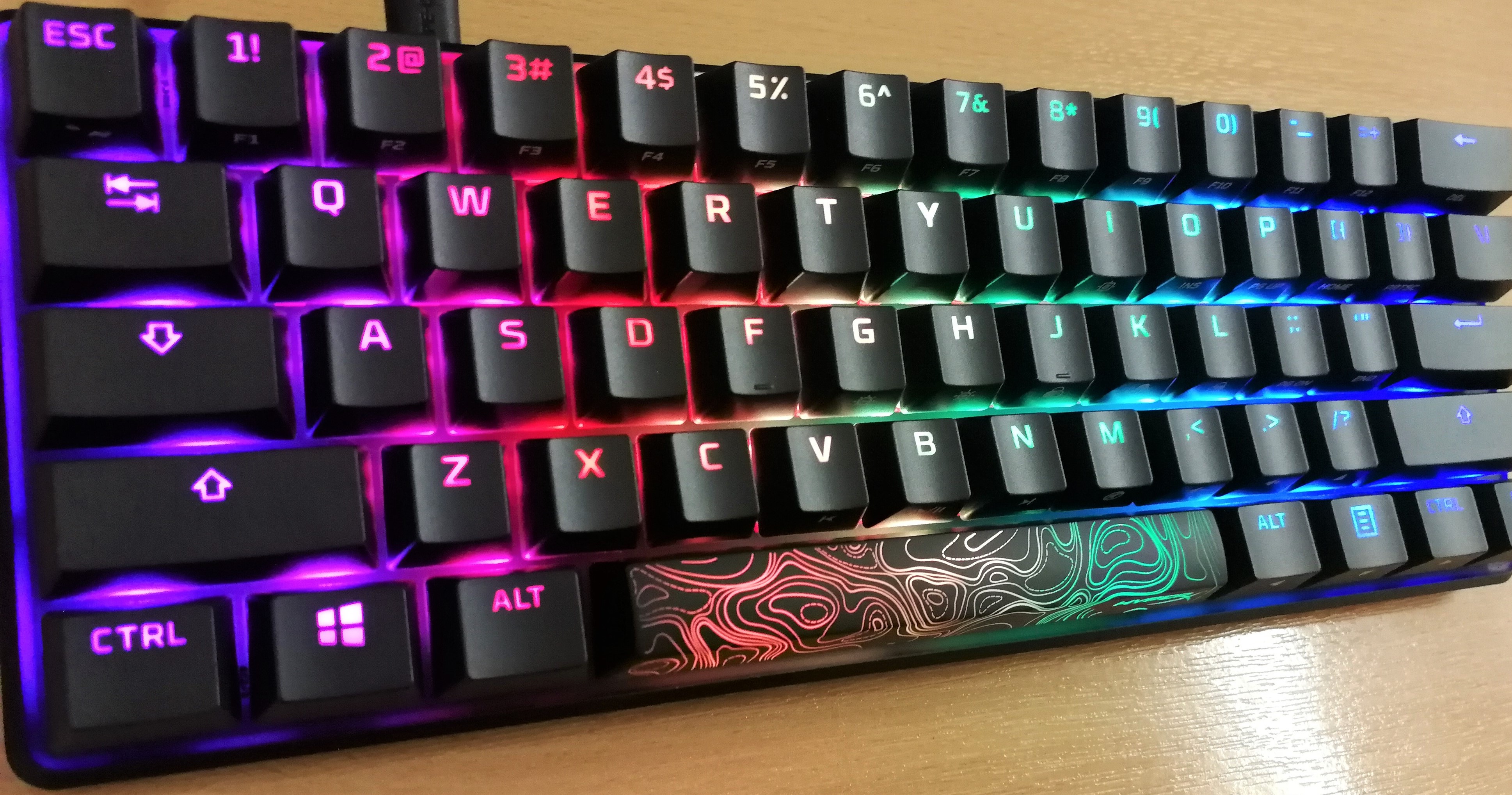 The Alloy Origins 60 keyboard, its keys glowing rainbow colours