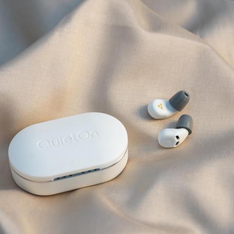 The QuietOn 3 earbuds in white, laying next to their case