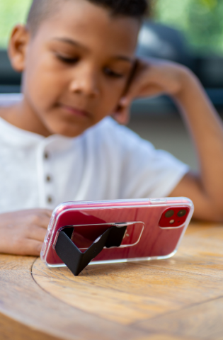 Young boy watching something on his phone using the CLCKR Stand and Grip