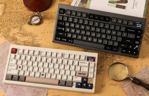 Two keyboards on a desk, one in white with grey, white and red keys, the other keyboard is black with black and grey keys