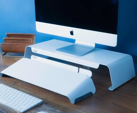 white desktop on white monitor risers, with a white panel in front and a keyboard 