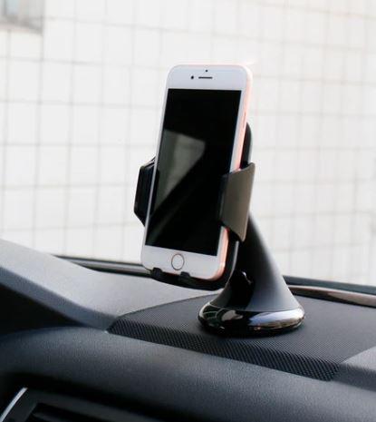 white smartphone on a black phone stand on a car dashboard
