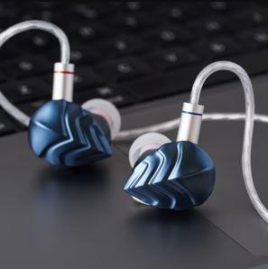 blue in-ear monitor ends with silver twisted cable coming from each on a grey surface 