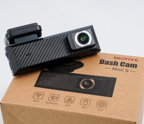 Small black bar shaped dash camera, on a cardboard box