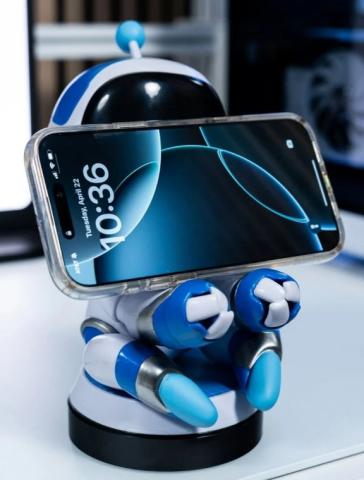 Astro Bot phone holder with mobile phone on the stand covering its face, on a white desk 