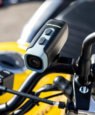 black and blue small camera on the mirror of a motorbike, the rest of the motorbike is blurred in the back of the picture but is yellow and black