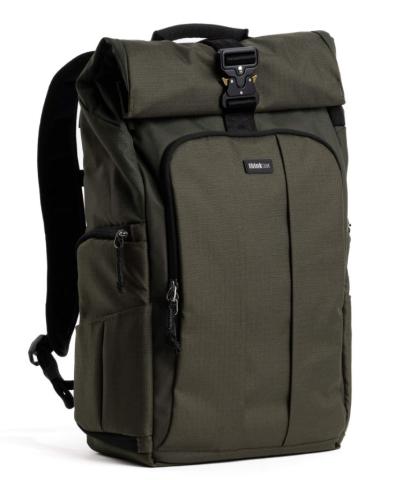 A dark green, rectangular backpack with a roll-top closure secured by a black buckle and a front zippered pocket. The backpack features padded shoulder straps, side zippered compartments, and a small logo patch centered on the front pocket.