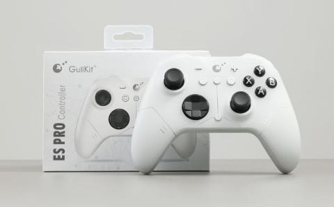 White gaming controller with black buttons and joysticks, displayed in front of its box