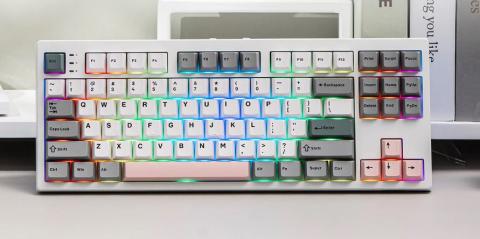 Image of a compact mechanical keyboard with white keycaps and RGB backlighting illuminating keys in multiple colors