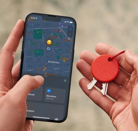 Image of hands with one holding keys with a red circular keyring on them, and the other hand holding a phone with a map image on it showing the location of the red circular keyring. 