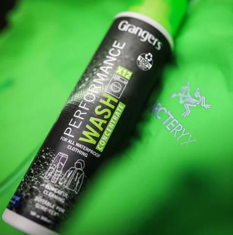 An image of Grangers Performance Wash Concentrate bottle laying on a bright green background. 