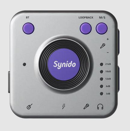 Image of compact audio interface device with a square silver body, with purple buttons, and a large purple dial in the center with "Synido" on it.