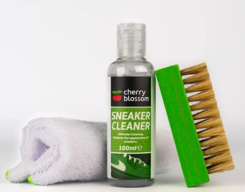 Image of white cloth, a green and black bottle labelled 'Cherry Blossom Sneaker Cleaner', and a green handled brush. The products are on a white background. 