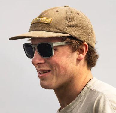 Image of person wearing a tan baseball cap and t-shirt, and grey/green sunglasses with dark grey lenses. 