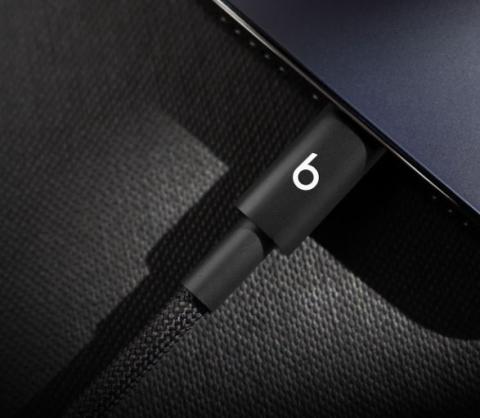 Close up image of a black charging cable plugged into a device, featuring a 'lowercase 'b' logo on the cable connector. 