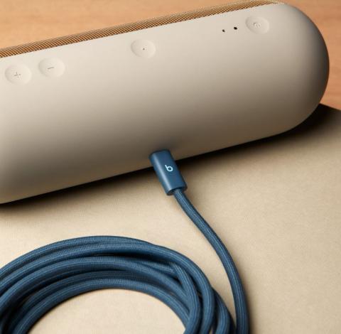 Image of blue charging cable plugged into light grey/beige portable speaker.