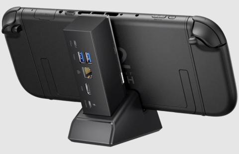 Image of black handheld gaming console docked in a compact docking station. The docking station has various ports at the back for HDMI, USB, Power input and Ethernet cables. 
