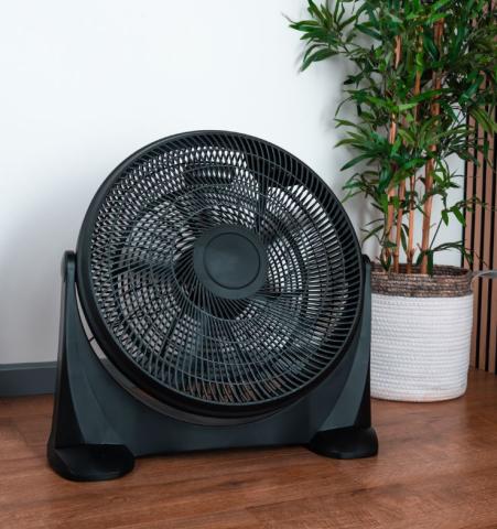 Image of large black floor fan on a wooden floor. 