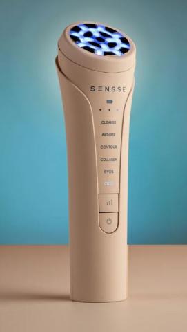 Image of light pink handheld skincare device labelled 'Sensse' with a circular head emitting blue light. On the front of the device there are different mode labels including Cleanse, Absorb, Contour, Collagen, Eyes and Cool. 