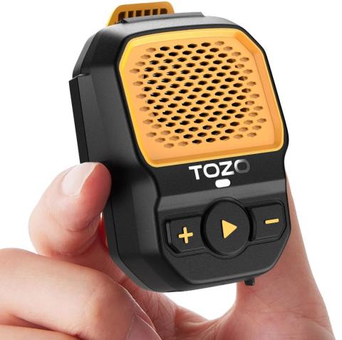 Image of small Bluetooth speaker in black with a yellow grill on the front, held between a thumb and forefinger. 