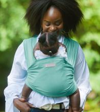 The Amawrap in mind green from the front. Mother and baby walk in the park.