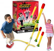 Two kids launch yellow and red Stomp Rockets, with the Stomp Rocket box in the background