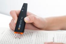 A hand uses the scanmarker air to scan text in a book