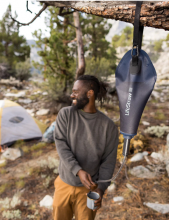 The LifeStraw Peak Series Gravity Water Filter System hanging off a branch. 