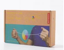 carboard box with persons arms holding a colourful disc suspended suspended on string