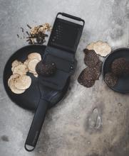 black truffle grating and slicing on a black plate on a stone table with slices and gratings from truffles around it 