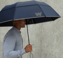 man holding navy umbrella with 'w' letter branding on one edge 