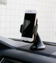 white smartphone on a black phone stand on a car dashboard
