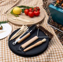 picnic table with a black carry bag with a range of metal and wooden grill tools on it 