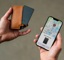 hands holding a leather look brown wallet with a black card poking out of it. n the other hand there is a mobile phone with a map on it showing the location of the card in the wallet 