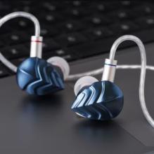blue in-ear monitor ends with silver twisted cable coming from each on a grey surface 