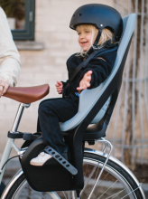 a child sitting in a rear-mounted child bike seat on the back of a bicycle