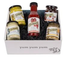 gift box filled with shredded black paper with a tomato ketchup bottle in the middle, a jar of picalilli in the top left corner, a jar of horseradish in the bottom left corner, a jar of chilli jam in the top right corner and a jar of beer mustard in the bottom right corner