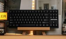 black keyboard with black keys on a wooden stand, on a desk 