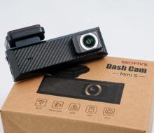Small black bar shaped dash camera, on a cardboard box