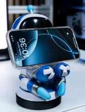 Astro Bot phone holder with mobile phone on the stand covering its face, on a white desk 