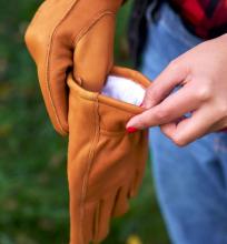 persons hands putting on leather gardening gloves