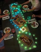 top view of table with string lights in blue and green across it, along with plates and food 