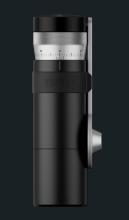 Image of cylindrical black coffee grinder with a silver dial on top marked with numbers for grind size, and a silver side mounted handle.