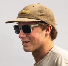 Image of person wearing a tan baseball cap and t-shirt, and grey/green sunglasses with dark grey lenses. 