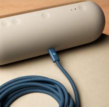 Image of blue charging cable plugged into light grey/beige portable speaker.