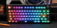 Image of black keyboard with RGB backlighting displaying a gradient of colours from red on the left to green on the right. The keyboard has a mini screen and rotary knob on the right hand side, 