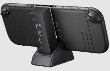 Image of black handheld gaming console docked in a compact docking station. The docking station has various ports at the back for HDMI, USB, Power input and Ethernet cables. 